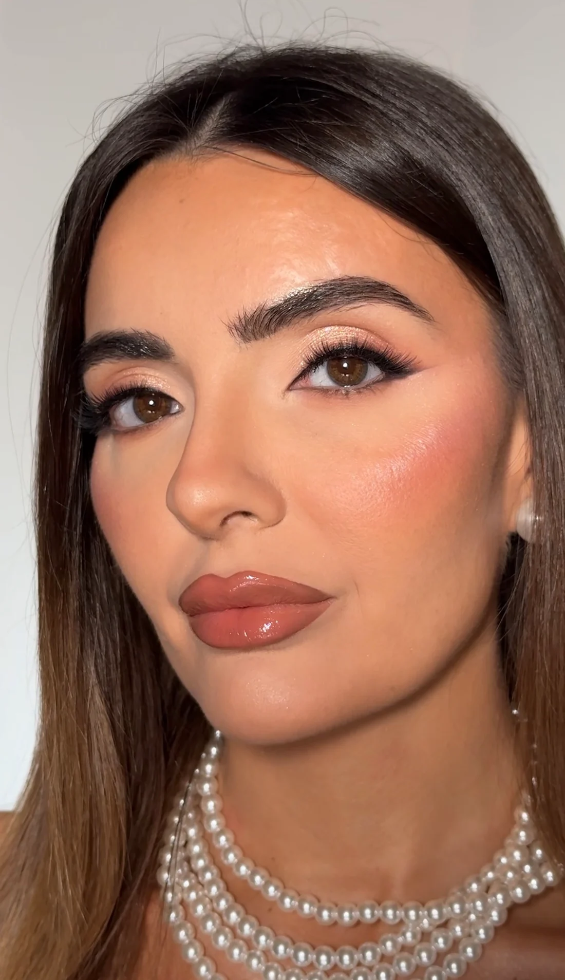 Makeup luminoso, labbra nude e collana di perle